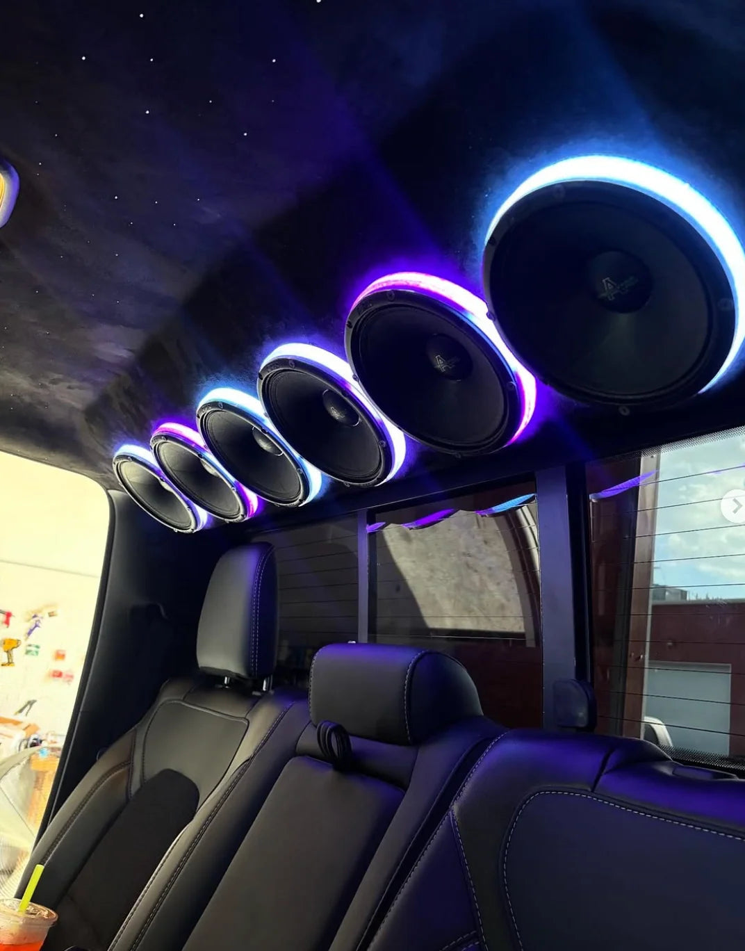 Car audio speaker rings with blue and purple LED halos, multiple circular drivers overhead